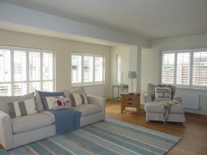 Sea Themed Living Room With White Plantation Shutters At Every Window