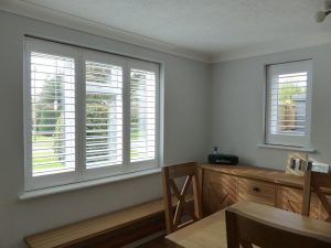 White Plantation Shutters On Two Windows In Dining Room