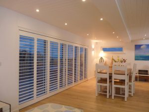 Tracked Plantation Shutters Across Wide Patio Doors In Dining Room