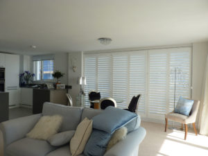 White Wooden Shutters On Living Room Patio Doors