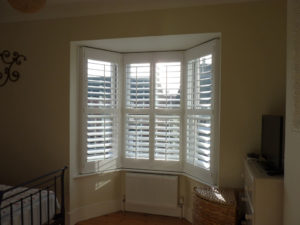 White Shutters On Angled Bay Window In Bedroom
