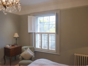 White Tier On Tier Shutters With Top Panels Open In Bedroom